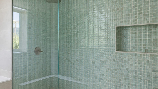 Frameless glass shower screen in front of green glass mosaic tiles
